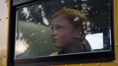 Redhead kid looking out school bus window Stock Footage 345618086