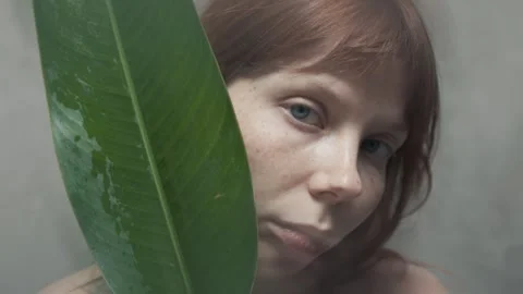 Redhead model posing with large tropical leaf Stock Footage 302047042
