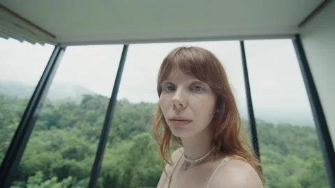 Redhead model posing by the window with forest view Stock Footage 303808071