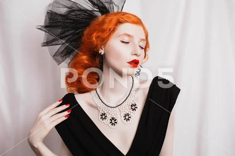 Redhead woman with unusual appearance in black dress and veil on the head and Stock Photos