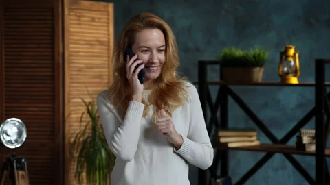 Redhead woman while standing in loft apartment talking on phone with her friend Stock Footage 162187916