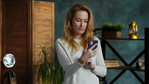 Redhead woman while standing in loft apartment talking on phone with her friend Stock Footage 162194401