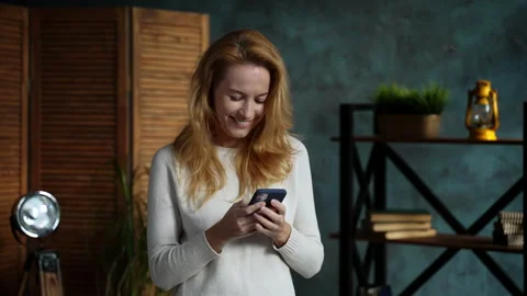 Redhead woman while standing in loft apartment chatting on phone with her friend Stock Footage 162384271