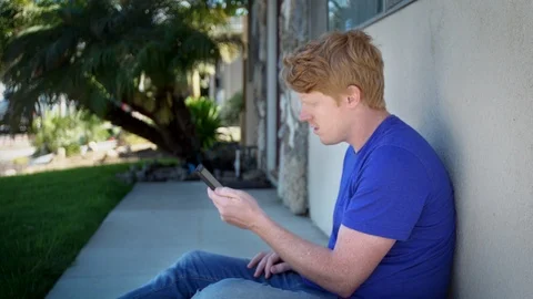 Redhead young man uses smart phone Stock Footage 111394757