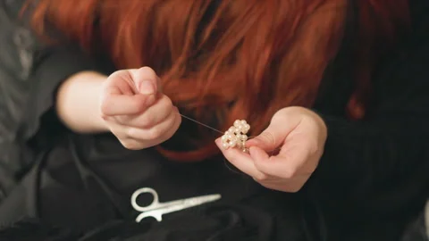 Redheaded artisan carefully fixing pearl necklace. Intimate scene of redheaded Stock Footage 346560070