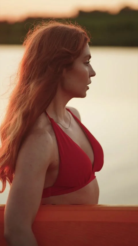 Redheaded woman in a red bikini posing on a paddleboard at sunset Stock Footage 341467913