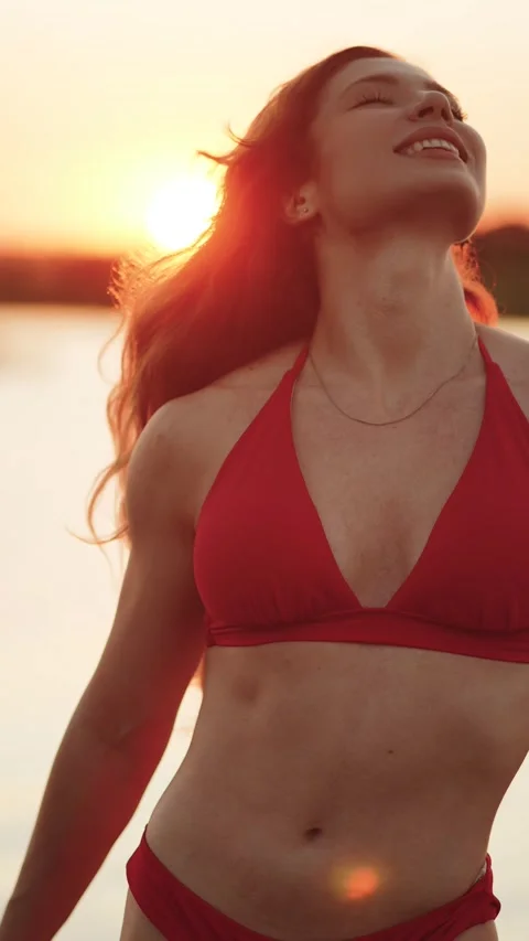 Redheaded woman in a red bikini posing on a paddleboard at sunset Stock Footage 341467973