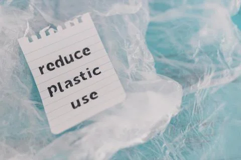 Reduce plastic use message on top of a bunch of plastic bags, sustainable liv Stock Photos