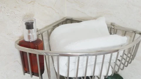 Reducing visual clutter. Bathroom corner shelf holding folded white towels and Video stock 338391488