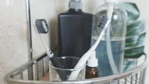 Reducing visual clutter. Toothbrushes in glass on bathroom shelf, displaying Video stock 338391242