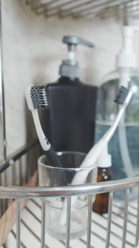 Reducing visual clutter. Toothbrushes in glass on bathroom shelf, promoting oral Video stock 338393724