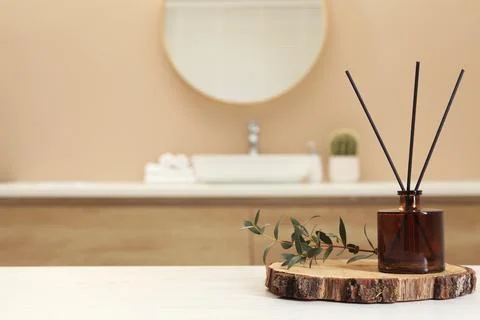 Reed diffuser and green twig on table in bathroom. Space for text Stock Photos