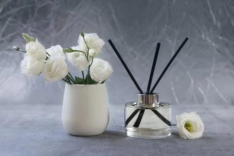 Reed diffuser and vase with eustoma flowers on gray marble table Stock Photos
