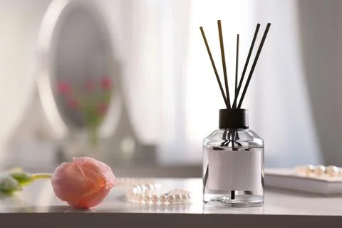 Reed diffuser, beautiful flower and pearl necklace on white table indoors. Sp Stock Photos