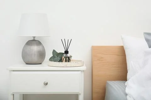 Reed diffuser with lamp and eucalyptus on nightstand in bedroom Stock Photos