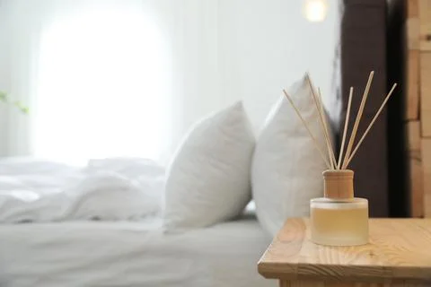 Reed diffuser on nightstand near bed in room. Modern interior Stock Photos