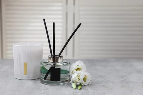 Reed diffuser, scented candle and eustoma flowers on gray marble table, space Stock Photos