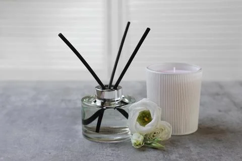 Reed diffuser, scented candle and eustoma flowers on gray marble table Stock Photos