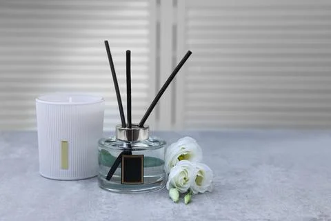 Reed diffuser, scented candle and eustoma flowers on gray marble table, space Stock Photos