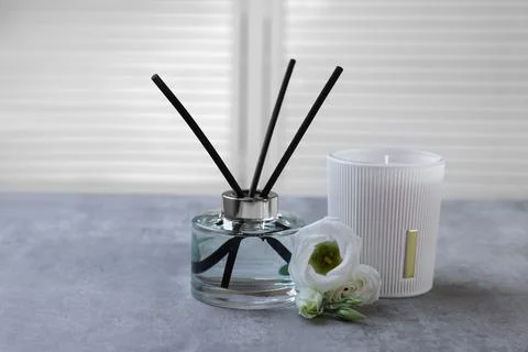 Reed diffuser, scented candle and eustoma flowers on gray marble table Stock Photos