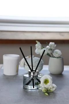 Reed diffuser, scented candle and eustoma flowers on gray marble table Stock Photos