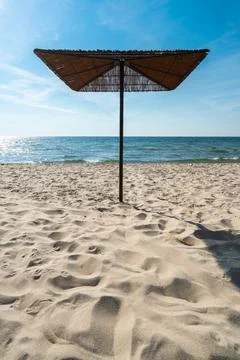 Reed sunshades on otherwise empty sandy beach on a beautiful sunny day of summer Stock Photos