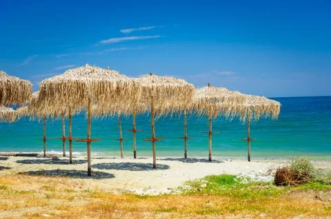 Reed umbrellas at empty beach Stock Photos