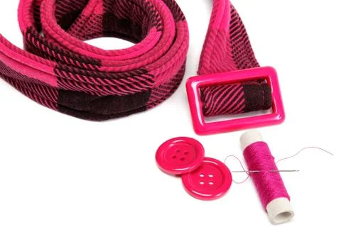 Reel of thread with a needle, buttons and a belt on a white background. Stock Photos