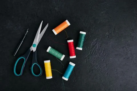 Reels of thread scattered on the table, tailors scissors and thread cutter, d Stock Photos