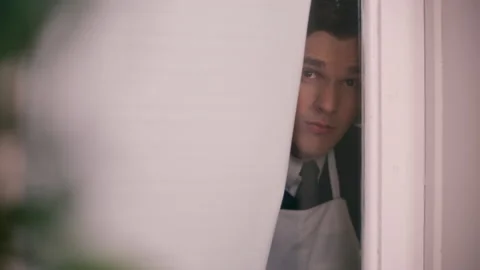 Reenactment: Slider shot of a man peeking out through a curtain, 1960s, Connecti Stock Footage 235317801