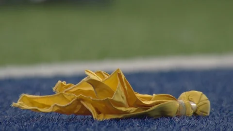 Referee picking up yellow penalty flag in end zone of football field Stock Footage 104773419