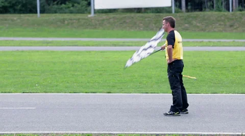 Referee signals the end of the race with checkered flag on a windy day Stock Footage 33065605