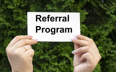 REFERRAL PROGRAM - words on a white sheet of paper in the hands of a girl on Stock Photos