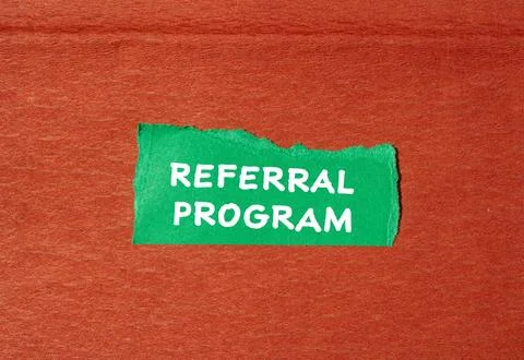 Referral program words written on green torn paper piece with brown background 스톡 사진