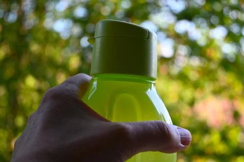 Refillable drinking bottle in hand outdoors Stock Photos