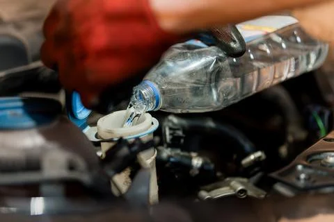 Refilling Engine Coolant in a Car with a Water Bottle Foto stock