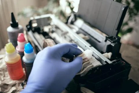 Refilling the printer with ink. Service and maintenance of equipment at home. Stock Photos