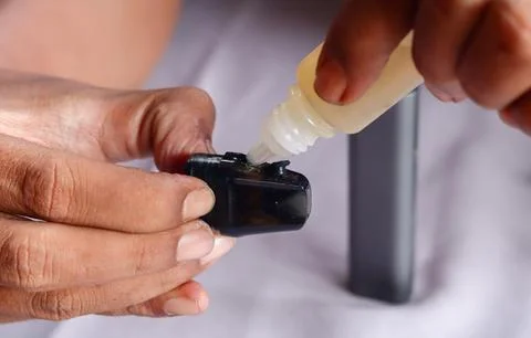 Refilling vape pod with e liquid Stock Photos