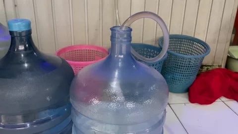 Refilling water into a large plastic gallon bottle Stockbeeldmateriaal 339525592