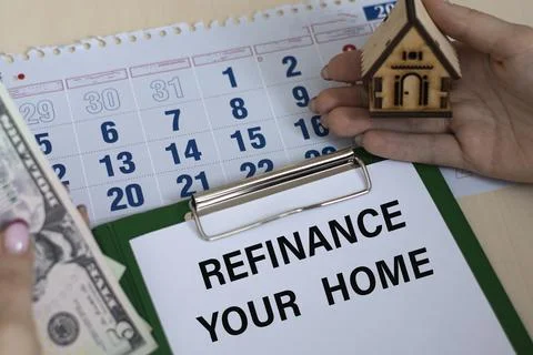 REFINANCE YOUR HOME - word in a folder against the background of women's hand Stock Photos