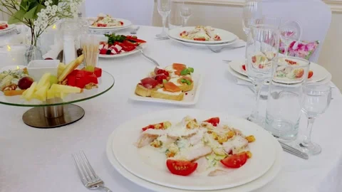 Refined dining table featuring caesar salad, fruit platters, canapes with Stock Footage 332570852