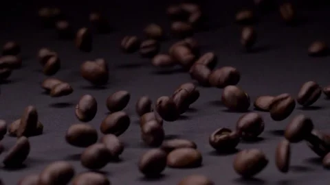 Refined. Slow motion shot of roasted brown coffee beans rolling, falling on dark Video stock 147412237