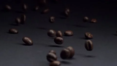 Refined. Slow motion shot of roasted brown coffee beans rolling, falling on dark Stock Footage 150567294