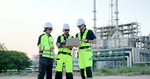 Refinery field team uses laptop, tablet, and walkietalkie while male engineer Stock Footage 335606346