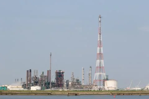Refinery installations with high torch next to the Scheldt Stock Photos