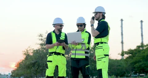 Refinery technician smiles while female engineer reviews laptop beside male Stock Footage 335606424