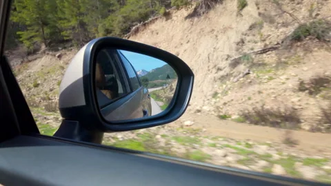 Reflected road landscape in car side mirror during road trip Stock Footage 335838349