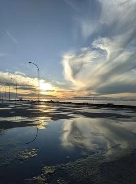 Reflected sunset sky and clouds create dramatic landscape with streetlights 스톡 사진