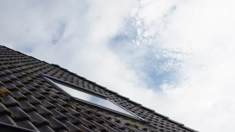 Reflecting clouds moving over a mossy tile roof with a skylight Vídeo Stock 336408475