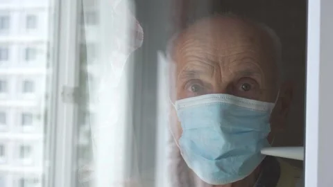 Reflection of aged man in blue mask standing at window Stock-Footage 134998245